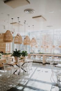 Coffee shop with a light brown colour them, with plants in light brown vases on the table